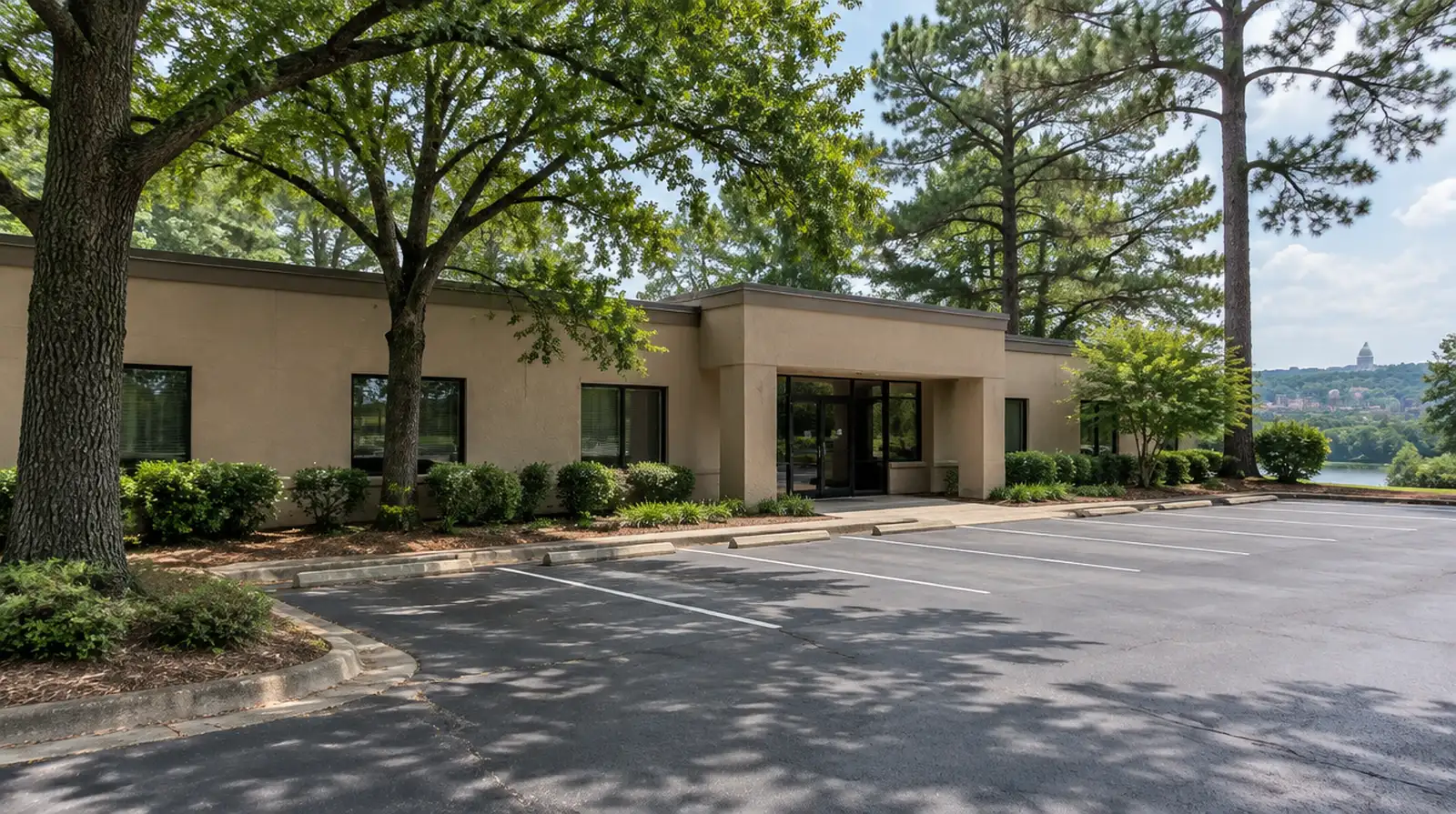 Mid-rise office building with beige stucco walls and a crew on a lift repairing a section near the roofline